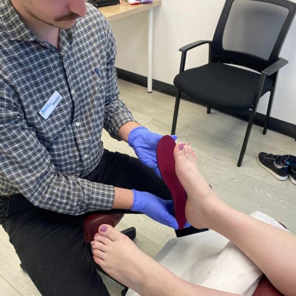 Adelaide Podiatrist, Sebastian Bower, checking the custom orthotic contour against a patient's foot