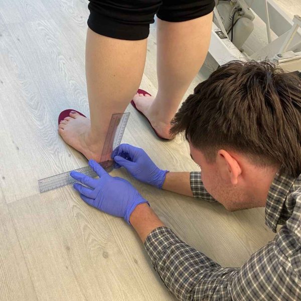 Adelaide Podiatrist, Sebastian Bower, measuring a patient standing on some custom orthotics